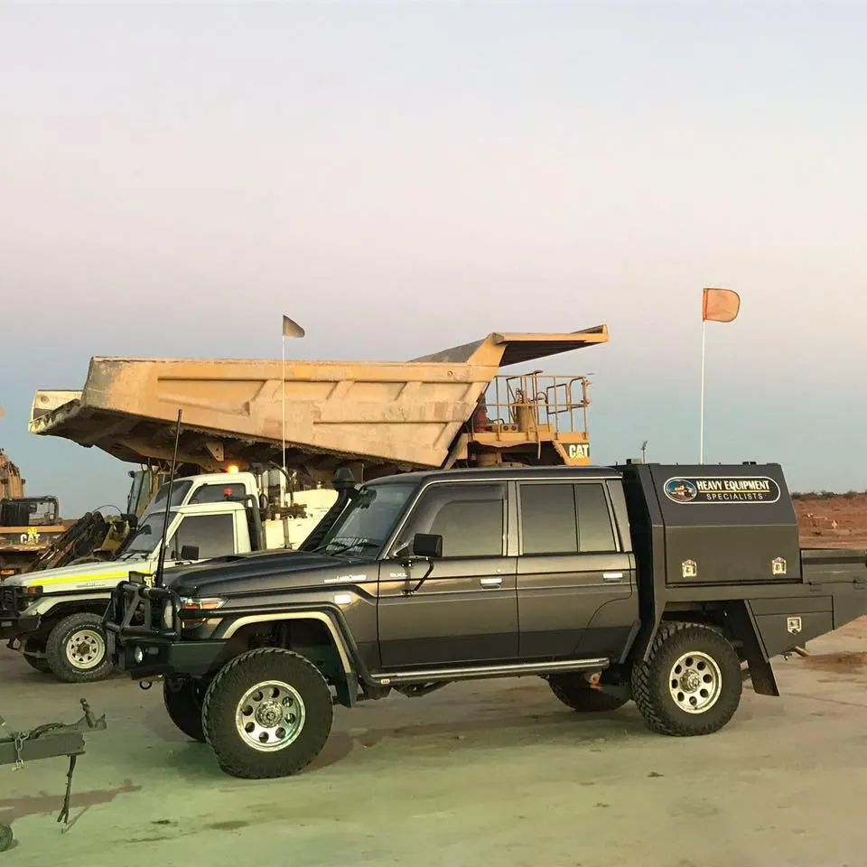 HES heavy equipment service vehicles beside a haul truck on a mine site at dusk